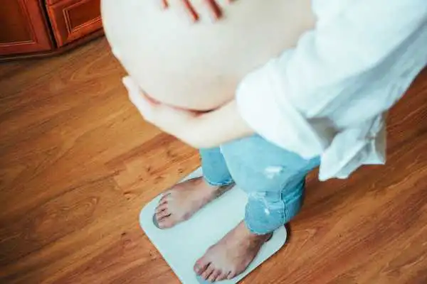 Image of woman weighing herself and experiencing weight gain through pregnancy Christchurch